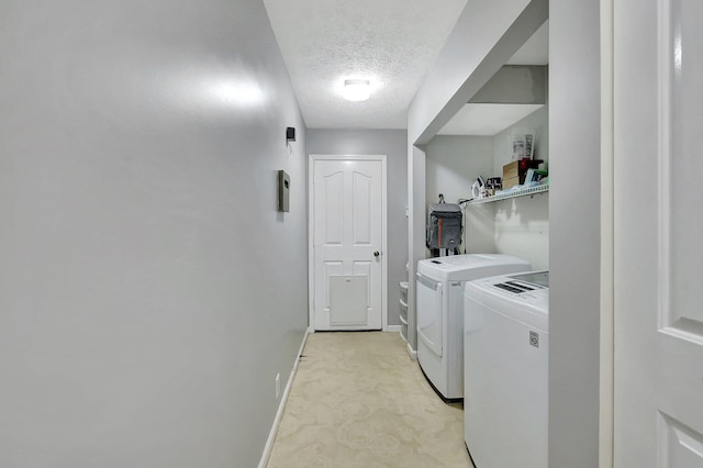 laundry area featuring light carpet, washer and dryer, a textured ceiling, baseboards, and laundry area