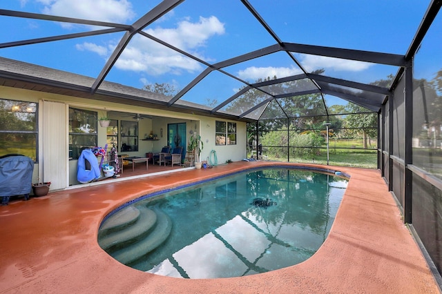 outdoor pool with glass enclosure, a patio, and a ceiling fan