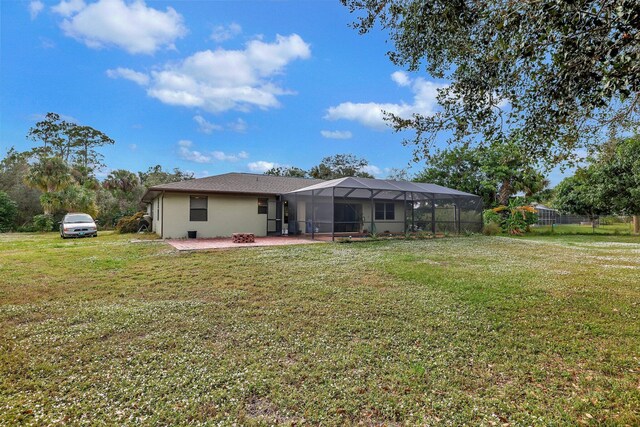 rear view of property with glass enclosure, fence, a patio area, and a lawn