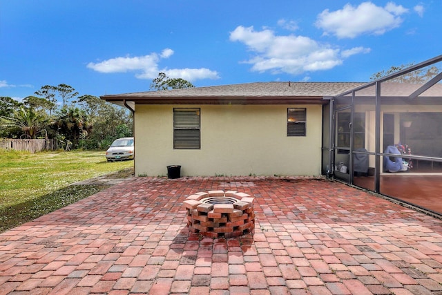 rear view of house with a shingled roof, stucco siding, a patio, a lawn, and a lanai