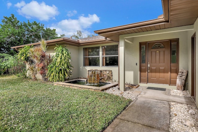 doorway to property featuring a lawn and stucco siding