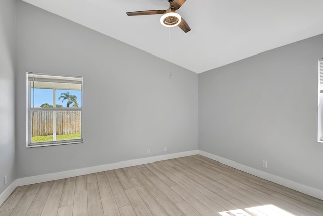 empty room with ceiling fan, vaulted ceiling, and light hardwood / wood-style flooring