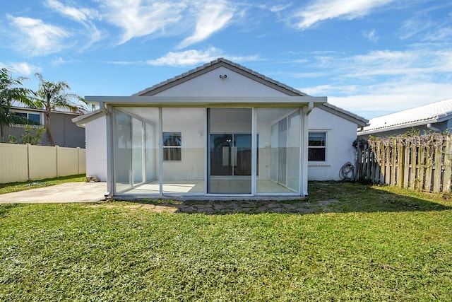 back of house with a sunroom, a patio area, and a lawn