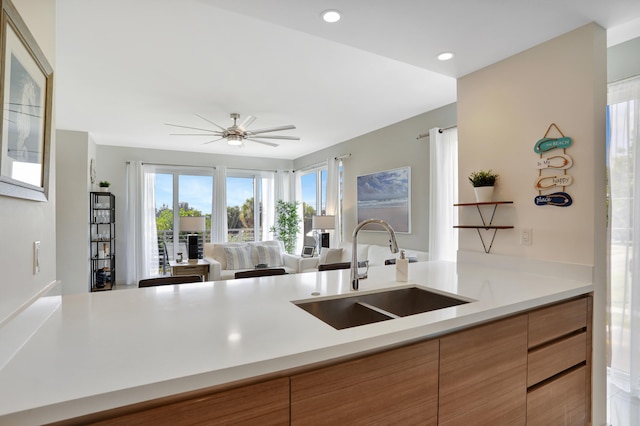 kitchen featuring kitchen peninsula, ceiling fan, and sink