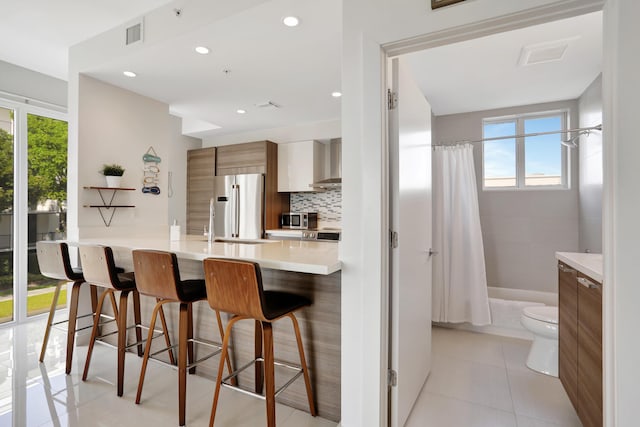 kitchen featuring a breakfast bar area, kitchen peninsula, a wealth of natural light, and appliances with stainless steel finishes