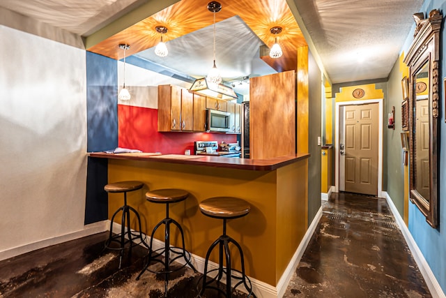 kitchen featuring a breakfast bar area, kitchen peninsula, hanging light fixtures, and stainless steel appliances