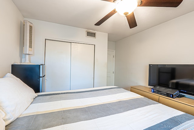 bedroom featuring ceiling fan, stainless steel refrigerator, and a closet