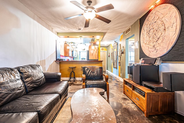 living room featuring ceiling fan and a textured ceiling