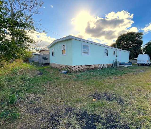 property exterior at dusk featuring a lawn and central AC