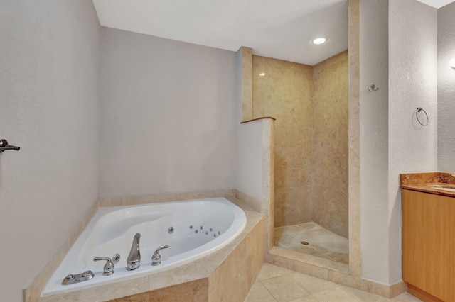 bathroom with tile patterned flooring, vanity, a walk in shower, and a whirlpool tub