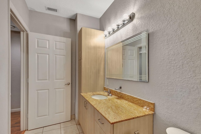 bathroom with toilet, vanity, and tile patterned floors