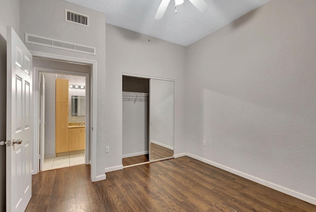 unfurnished bedroom with ceiling fan, dark hardwood / wood-style flooring, a textured ceiling, and a closet