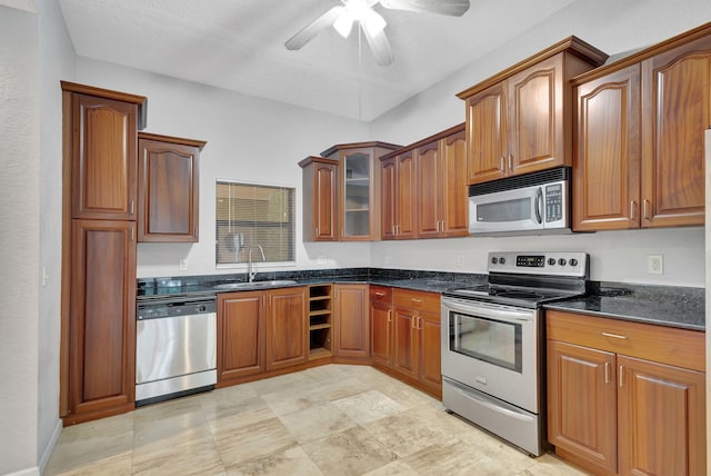 kitchen with a textured ceiling, stainless steel appliances, ceiling fan, sink, and dark stone countertops