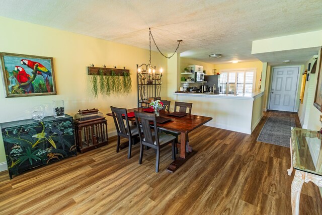 dining space with an inviting chandelier, a textured ceiling, baseboards, and wood finished floors