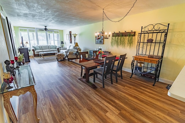 dining room featuring a textured ceiling, ceiling fan with notable chandelier, wood finished floors, and baseboards