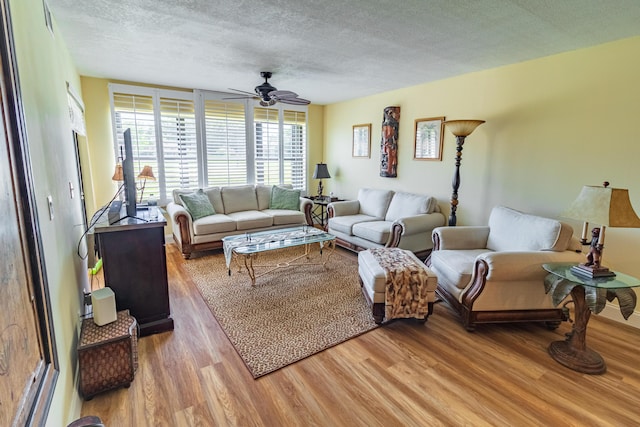 living room featuring light wood-style flooring, a ceiling fan, and a textured ceiling