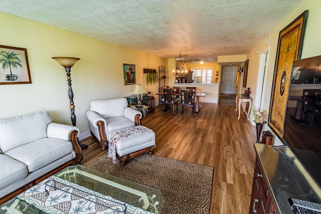 living area with a textured ceiling, baseboards, wood finished floors, and a chandelier