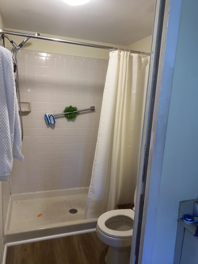 bathroom with a shower with shower curtain, hardwood / wood-style floors, and toilet