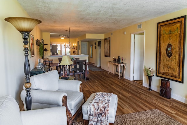 living room with dark wood-style floors, a textured ceiling, visible vents, and a notable chandelier