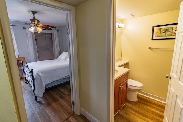 bathroom with ceiling fan, toilet, wood finished floors, vanity, and baseboards