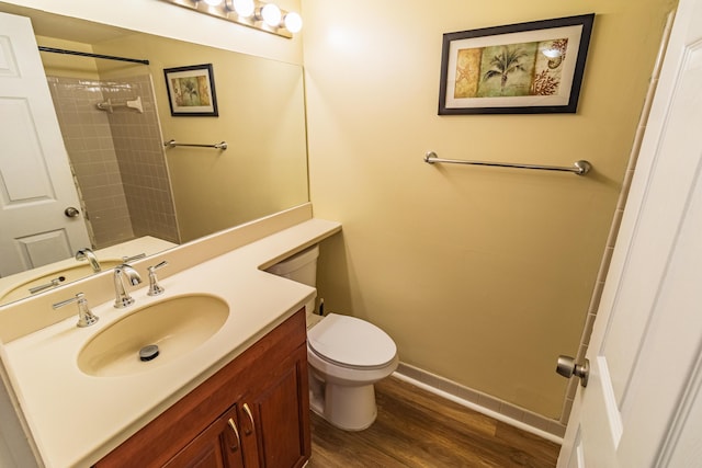 full bath featuring toilet, wood finished floors, vanity, baseboards, and walk in shower