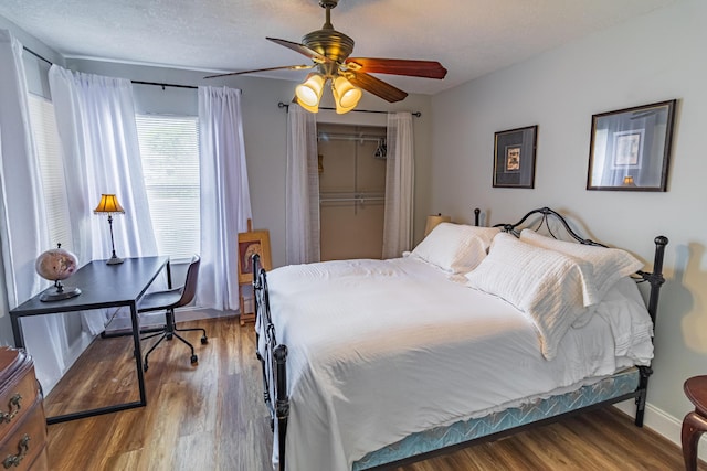 bedroom with ceiling fan, a textured ceiling, baseboards, and wood finished floors