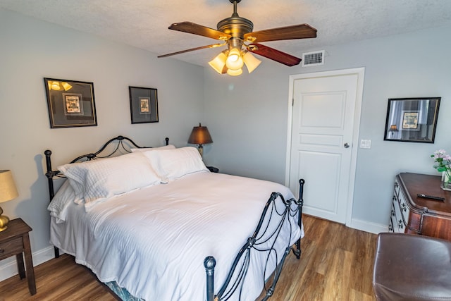 bedroom with visible vents, a textured ceiling, and wood finished floors