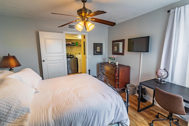 bedroom with visible vents, a ceiling fan, a textured ceiling, separate washer and dryer, and wood finished floors