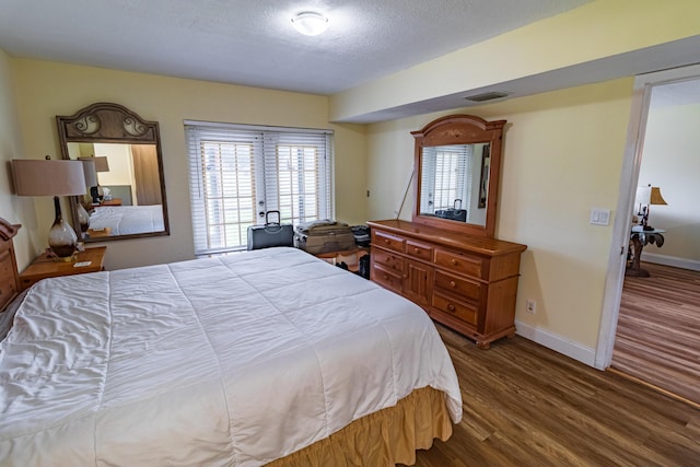 bedroom featuring a textured ceiling, wood finished floors, visible vents, and baseboards