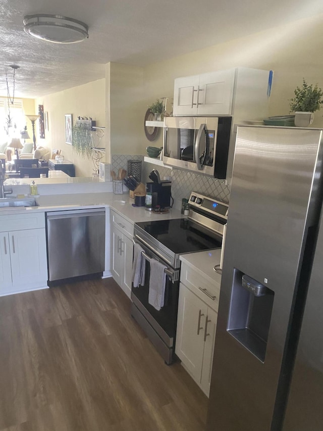 kitchen with white cabinets, kitchen peninsula, dark wood-type flooring, and appliances with stainless steel finishes