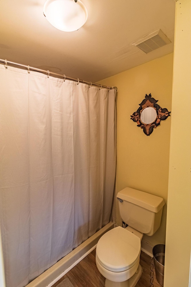 bathroom featuring toilet, wood finished floors, visible vents, and shower / tub combo with curtain