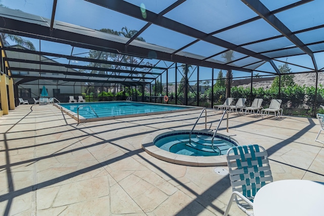 pool with a community hot tub, a patio, and glass enclosure