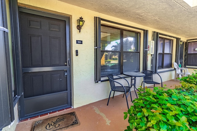 property entrance featuring a porch and stucco siding