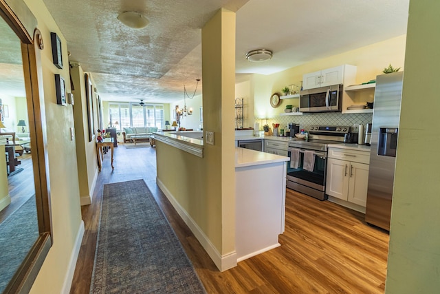 kitchen featuring open floor plan, dark wood-style flooring, stainless steel appliances, open shelves, and backsplash