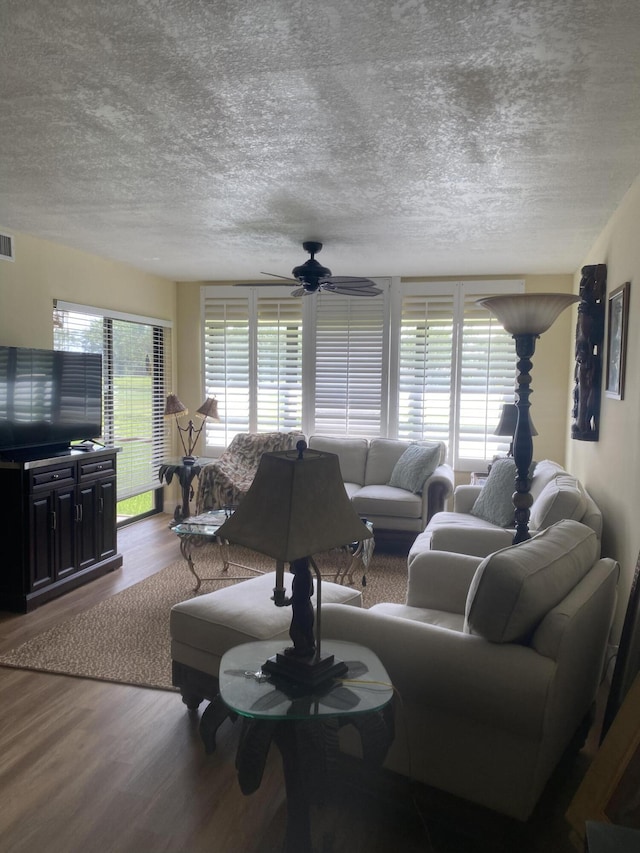 living room with hardwood / wood-style floors, ceiling fan, and a textured ceiling