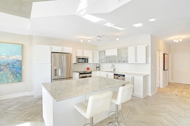 kitchen featuring white cabinetry, sink, light stone counters, a breakfast bar area, and appliances with stainless steel finishes