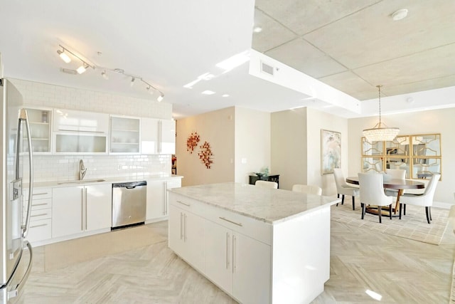 kitchen featuring white cabinets, a center island, stainless steel appliances, and hanging light fixtures