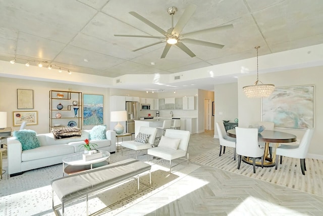 living room with ceiling fan with notable chandelier and light parquet flooring