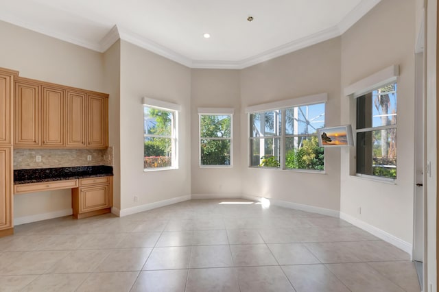 unfurnished dining area featuring built in desk, crown molding, and light tile patterned flooring