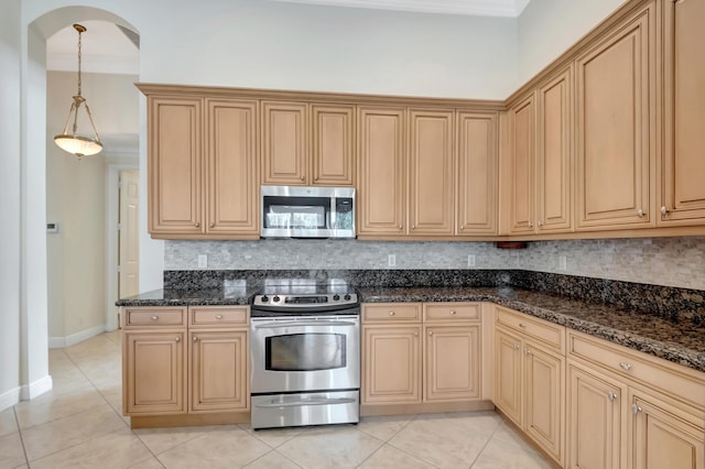 kitchen with light tile patterned floors, stainless steel appliances, hanging light fixtures, and dark stone countertops