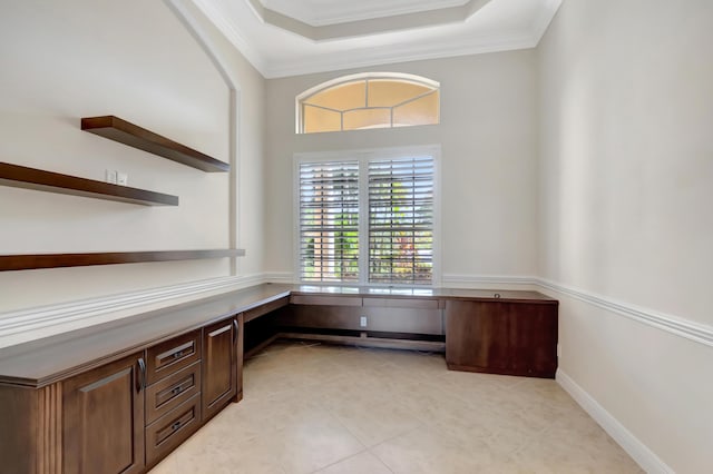 unfurnished office featuring crown molding, light tile patterned floors, and built in desk