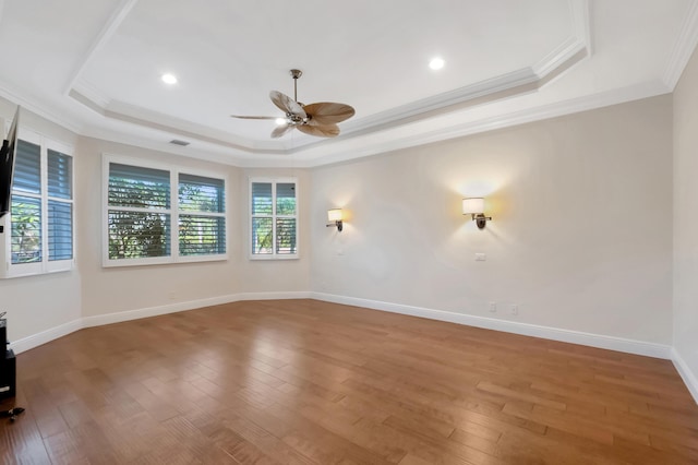 unfurnished room featuring hardwood / wood-style flooring, a raised ceiling, ceiling fan, and crown molding