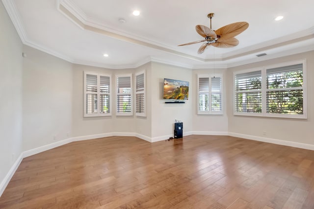 unfurnished living room featuring a tray ceiling, ceiling fan, hardwood / wood-style flooring, and ornamental molding