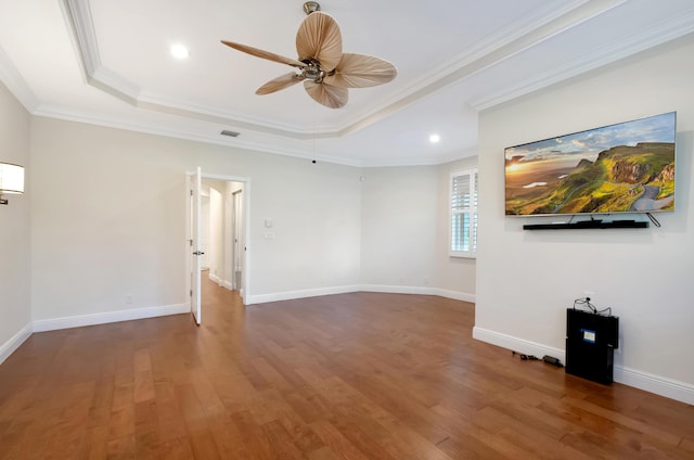 unfurnished room featuring hardwood / wood-style floors, ceiling fan, crown molding, and a tray ceiling