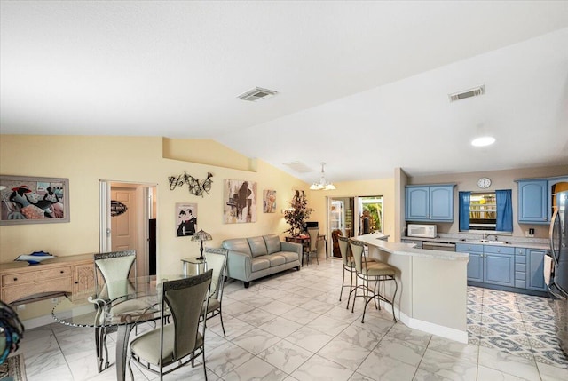 living room featuring an inviting chandelier, sink, and vaulted ceiling