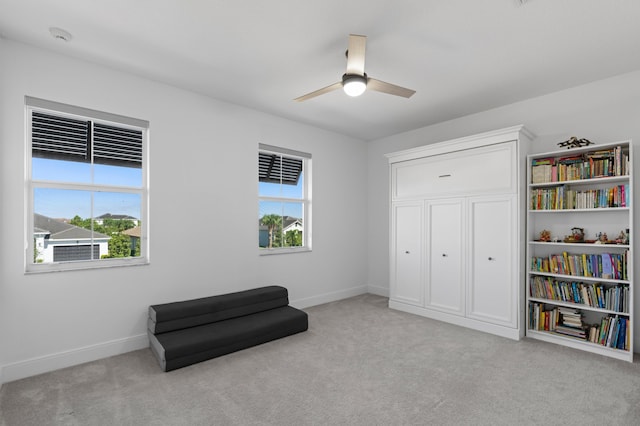 living area with light colored carpet and ceiling fan