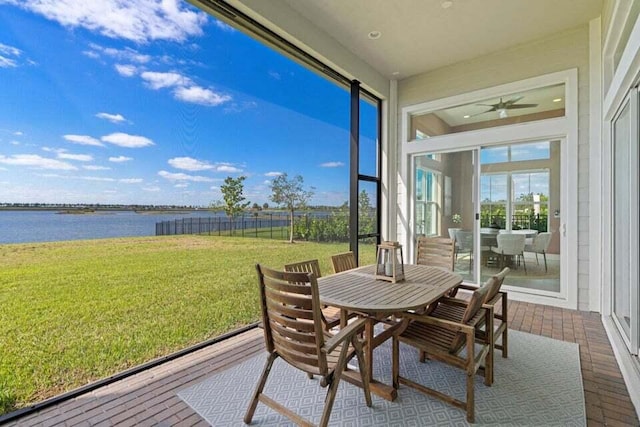 sunroom with ceiling fan and a water view