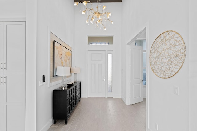 entryway with a towering ceiling, an inviting chandelier, and light hardwood / wood-style flooring