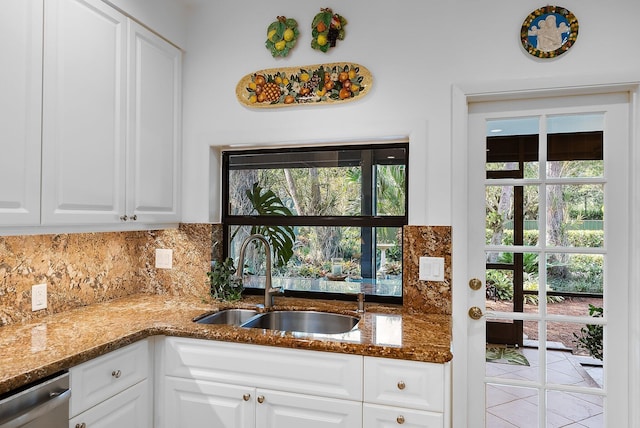 kitchen featuring sink, stainless steel dishwasher, dark stone countertops, tasteful backsplash, and white cabinetry