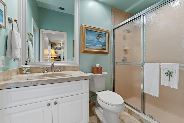 bathroom featuring tile patterned flooring, vanity, toilet, and a shower with door